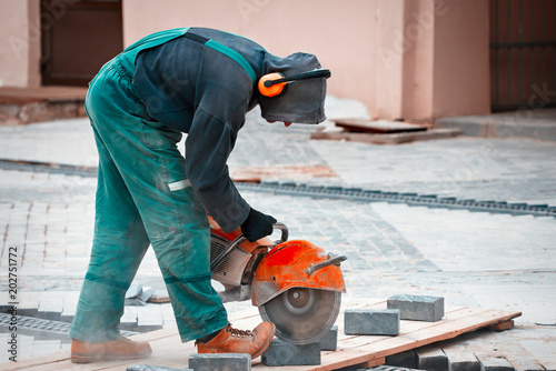 Construction worker cuts walkway slab with circular saw. Man Protect Hearing From Noise Hazards on the Job