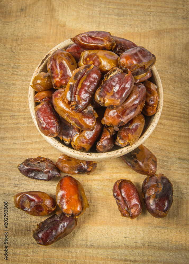 Dry dates fruit in the bowl, on the wood background. Dry dates fruit in the bowl, on the wood background.