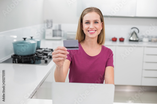 Gleeful casual woman using laptop and credit card