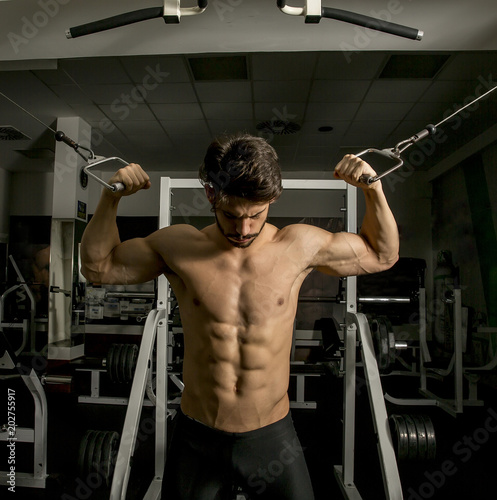 Muscular man in gym doing exercises for biceps