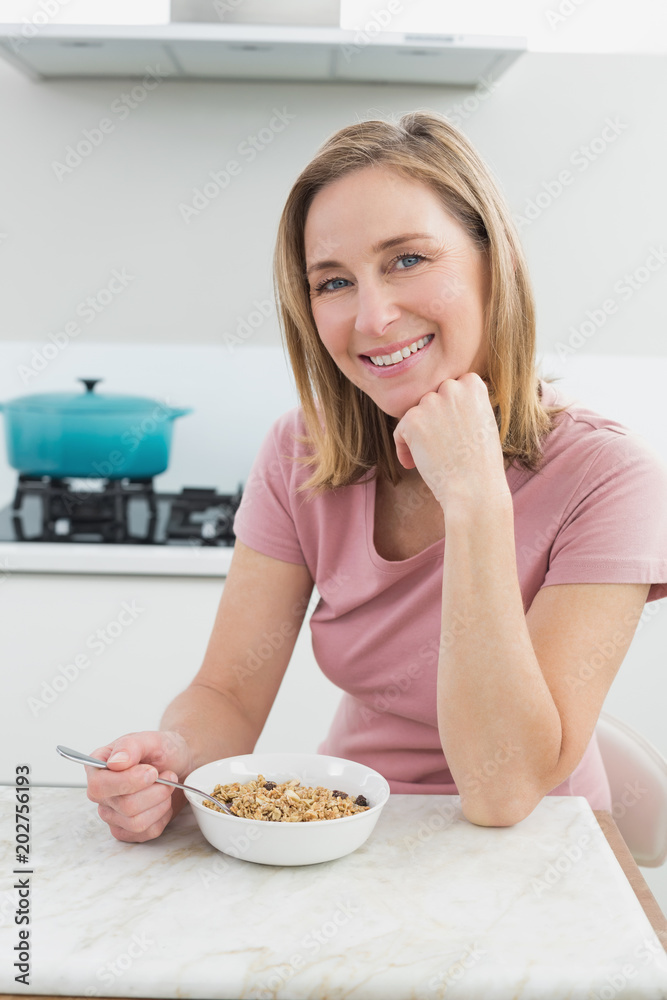 Smiling woman having cereals in the kitchen