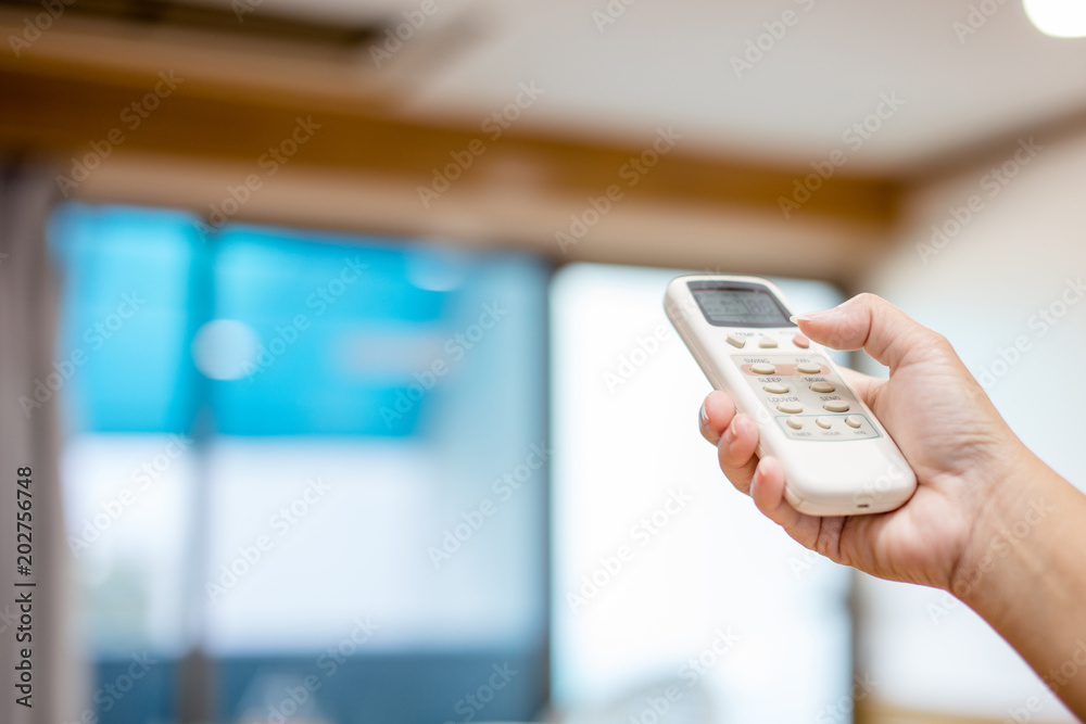 Remote air conditioning in the hand of a woman pressing open.