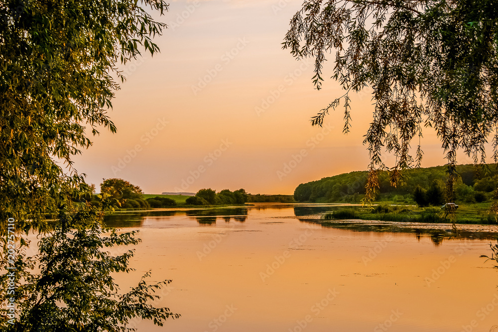 Sunset on  river. Trees on both sides of  river_