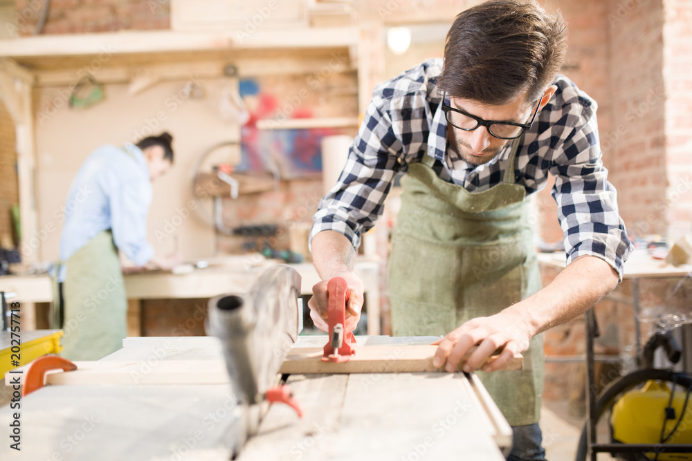 Portrait of focused modern carpenter working with wood in joinery shop, copy space Portrait of focused modern carpenter working with wood in joinery shop, copy space
