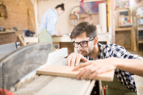 Фотография Portrait of focused handsome carpenter working with wood in modern  joinery shop