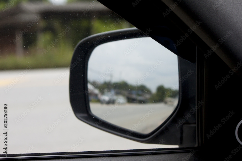 Car parking on the road and view from mirror beside car.