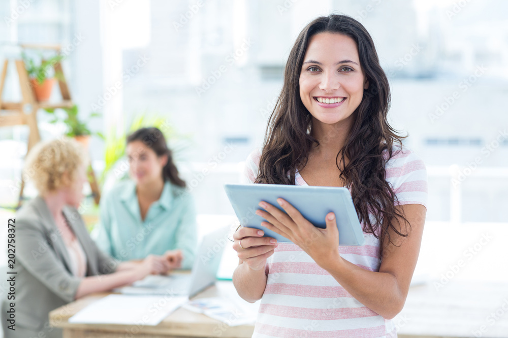 Smiling businesswoman using a tablet with colleagues Smiling businesswoman using a tablet with colleagues