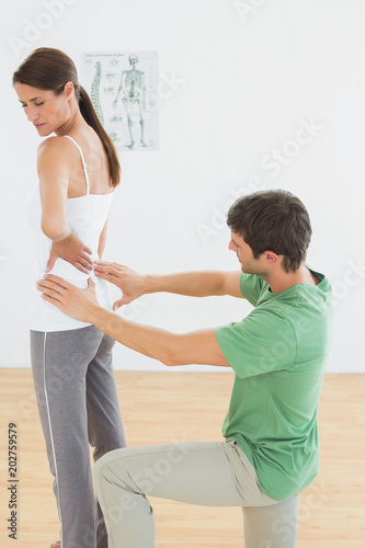 Physiotherapist examining womans back in medical office