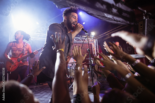 Male singer performing on stage by crowd at nightclub photo
