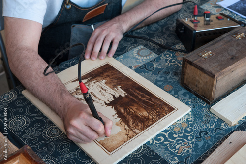Artisan at work with his wood burning tool. The Pyrography is an engraving technique by means of a heat source, on wood, leather, cork and other materials photo