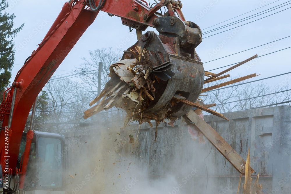 Φωτογραφία old house being demolished by a large backhoe