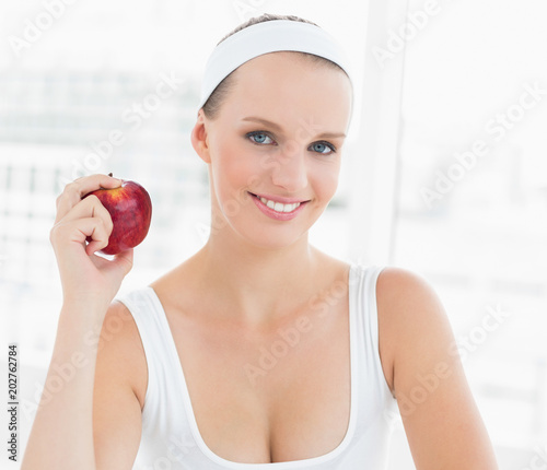 Smiling pretty sportswoman holding an apple