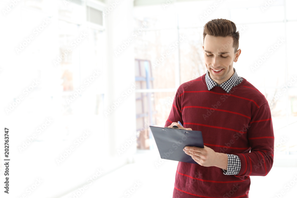Male real estate agent with clipboard indoors Male real estate agent with clipboard indoors