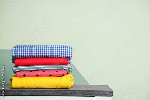 Quadro su tela Stack of clean clothes on table against light background