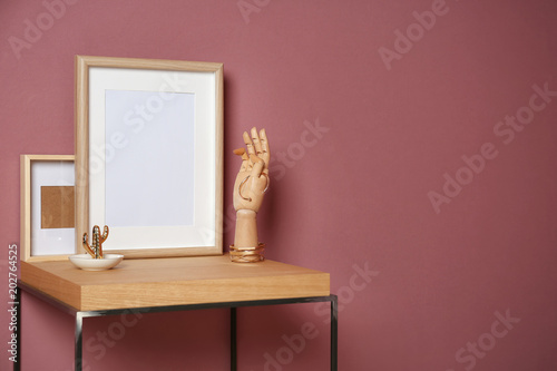 Mockup of blank frame and wooden hand on table