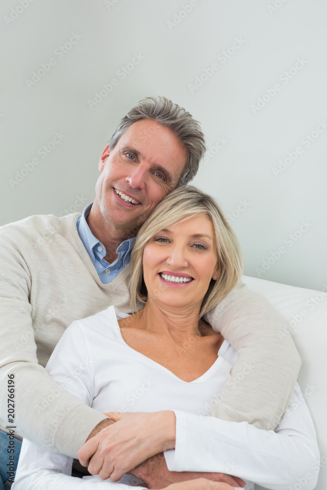 Happy couple embracing while sitting on sofa at home Happy couple embracing while sitting on sofa at home