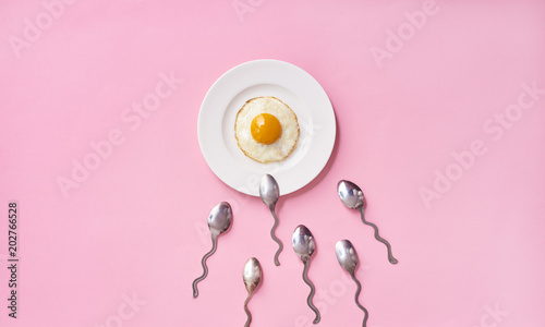 Conception of fertilization. Fried egg in white plate, and spoon photo