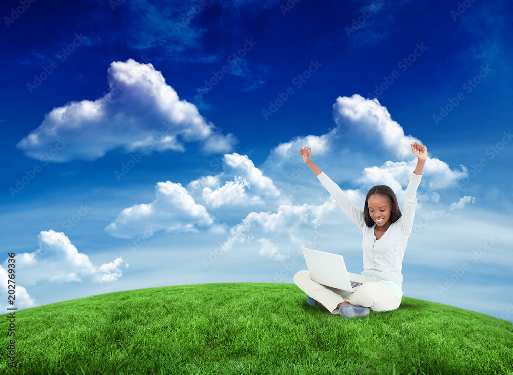 Fotografie Young woman stretching while on the floor with her laptop against green field un