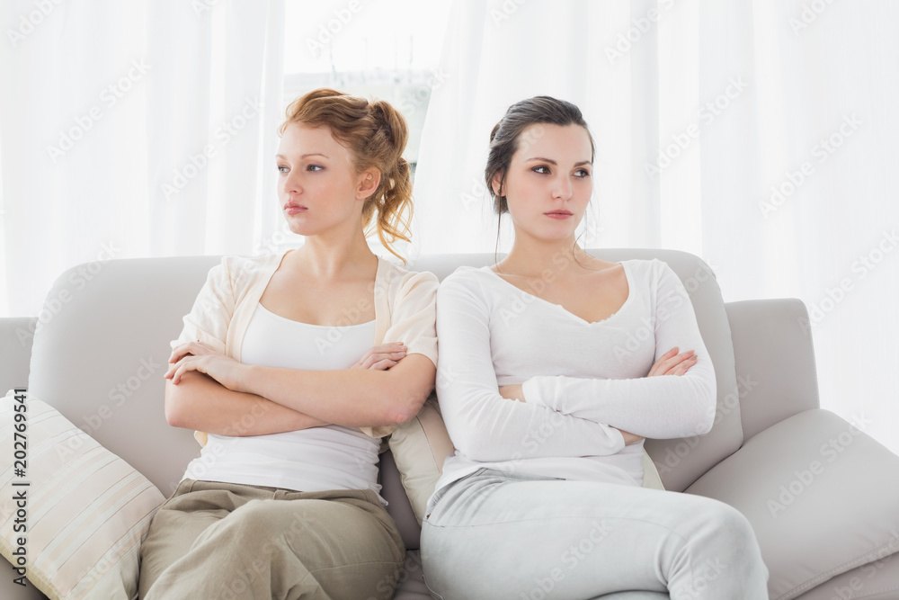 Unhappy friends not talking after argument on couch