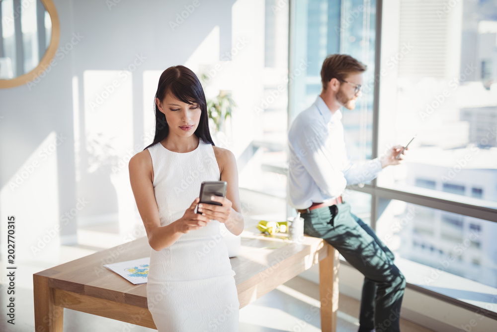 Fototapeta premium Attentive executives using mobile phone at desk