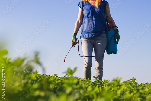 Fotografie Gardener woman spraying field with pesticide
