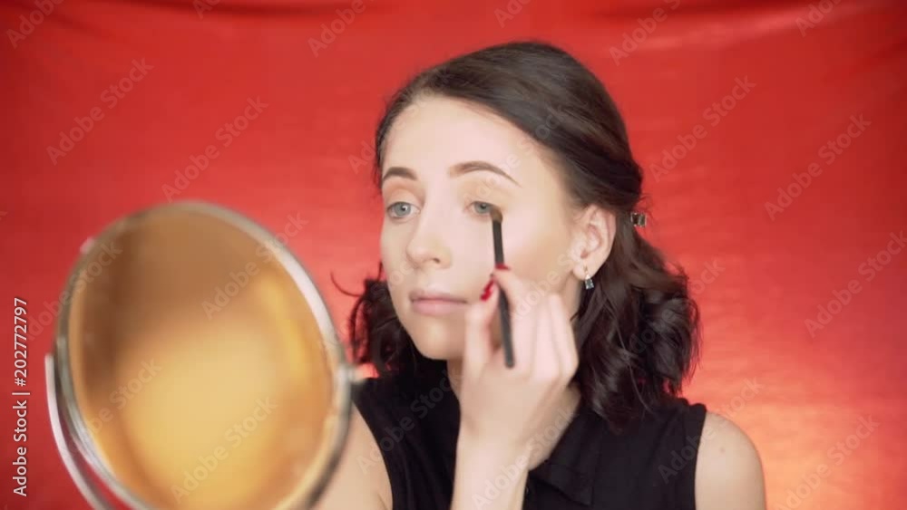 beautiful girl doing makeup on a red background beautiful girl doing makeup on a red background
