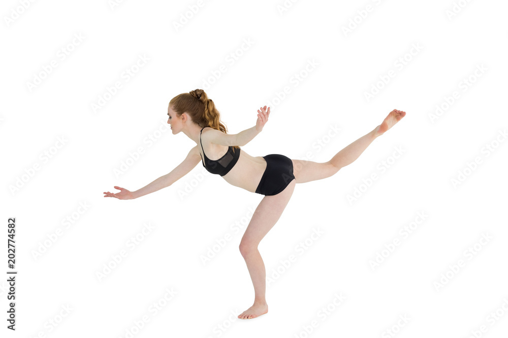 Side view of a sporty young woman standing on one leg
