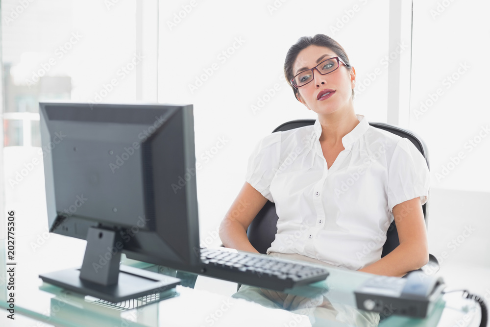 Frowning businesswoman sitting at her desk looking at computer