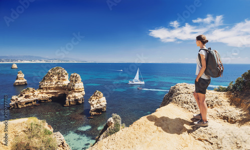 Young woman traveler looking at the sea in Lagos town, Algarve region, Portugal. Travel and active lifestyle concept
