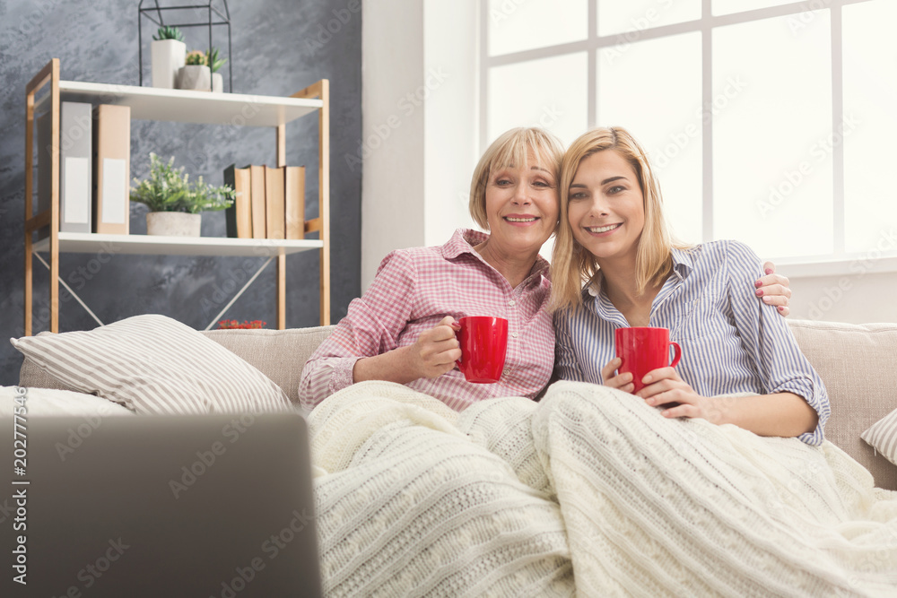 Happy adult mother and daughter watching film at home. Happy adult mother and daughter watching film at home.