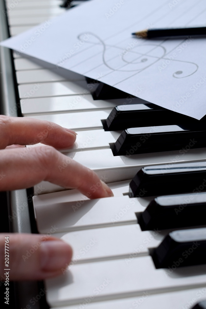 Fototapeta premium Black and white piano keys and musician's hands are playing a tune