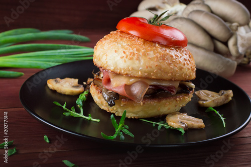 Fototapeta Naklejka Na Ścianę i Meble -  Burger with fried mushrooms, ham, onions and cheese on rustic background