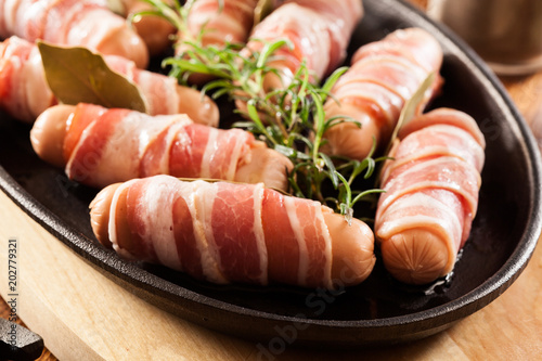 Raw mini sausages wrapped in smoked bacon