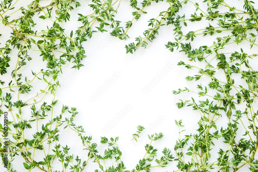 Overhead view of thyme leaves and twigs arranged in frame form with text space on white background