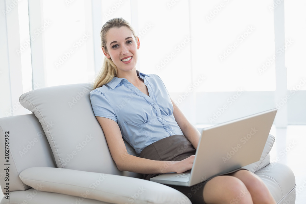 Beautiful chic businesswoman using her notebook sitting on couch Beautiful chic businesswoman using her notebook sitting on couch