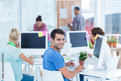 Smiling young man working with her colleague at desk in the office