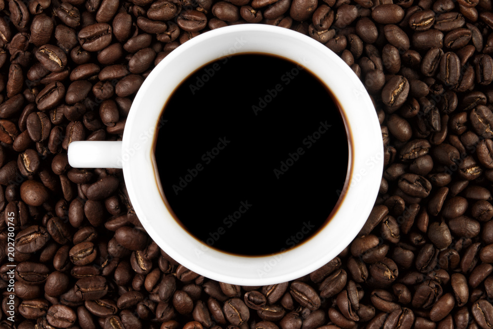 Cup filled with coffee on coffee beans background. Top view. Cup filled with coffee on coffee beans background. Top view.