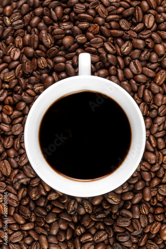 Cup filled with coffee on coffee beans background. Top view.