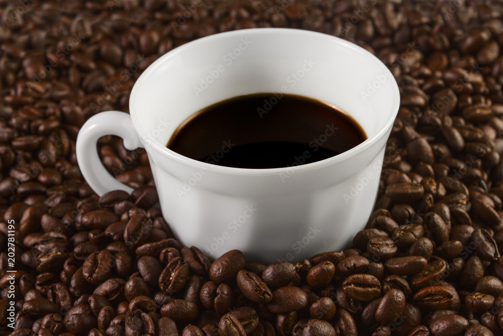Cup filled with coffee on coffee beans background. Selective focus. Cup filled with coffee on coffee beans background. Selective focus.