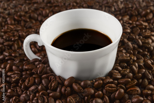 Cup filled with coffee on coffee beans background. Selective focus.