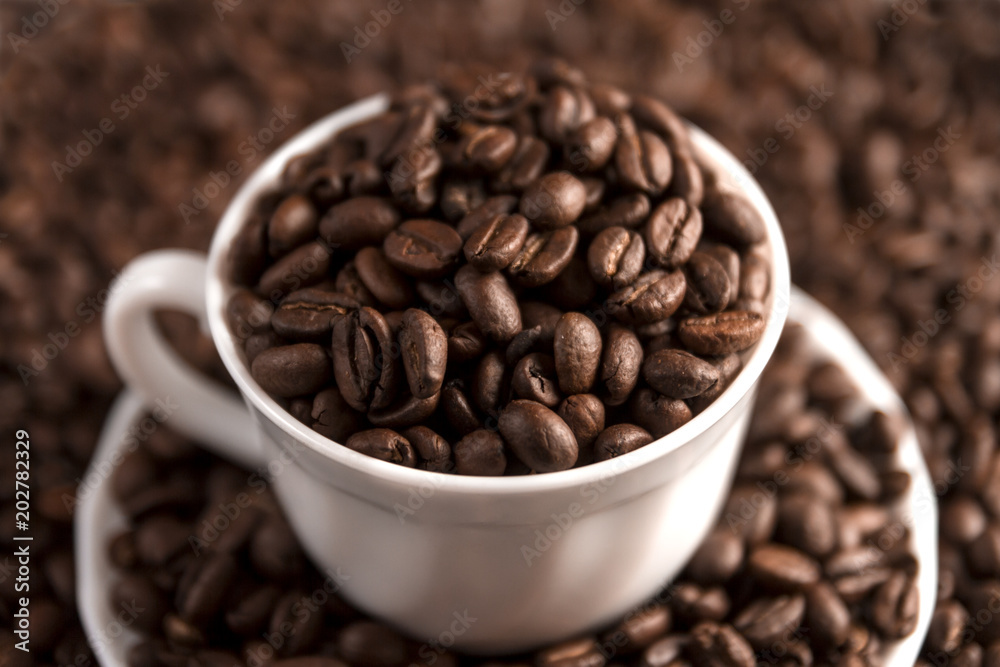 Cup filled with coffee beans on coffee beans background. Selective focus.