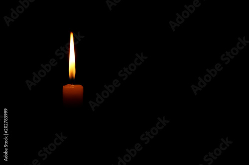 Burning candle on black background