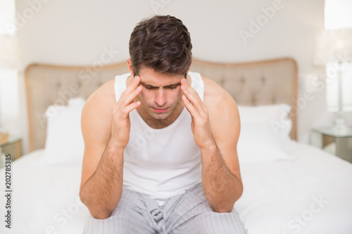 Young man suffering from headache in bed © WavebreakmediaMicro