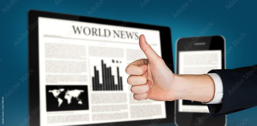 Hand showing thumbs up against digital tablet and smartphone showing news Hand showing thumbs up against digital tablet and smartphone showing news