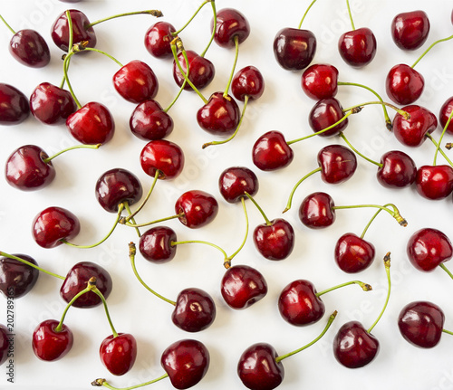 Fresh red cherries lay on white isolated background with copy space. Background of cherries. Ripe cherry on a white background. Cherries with copy space for text. Top view. Cherry fruit.