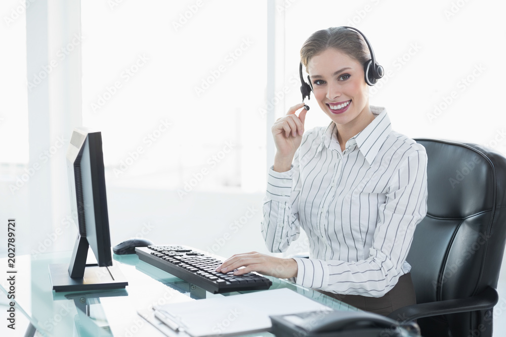 Gorgeous chic agent wearing headset sitting at her desk Gorgeous chic agent wearing headset sitting at her desk