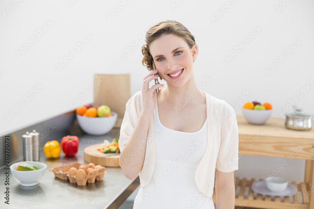 Content young woman honing while standing in kitchen Content young woman honing while standing in kitchen