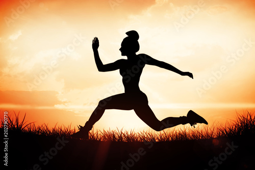 Fit brunette running and jumping against orange sunrise