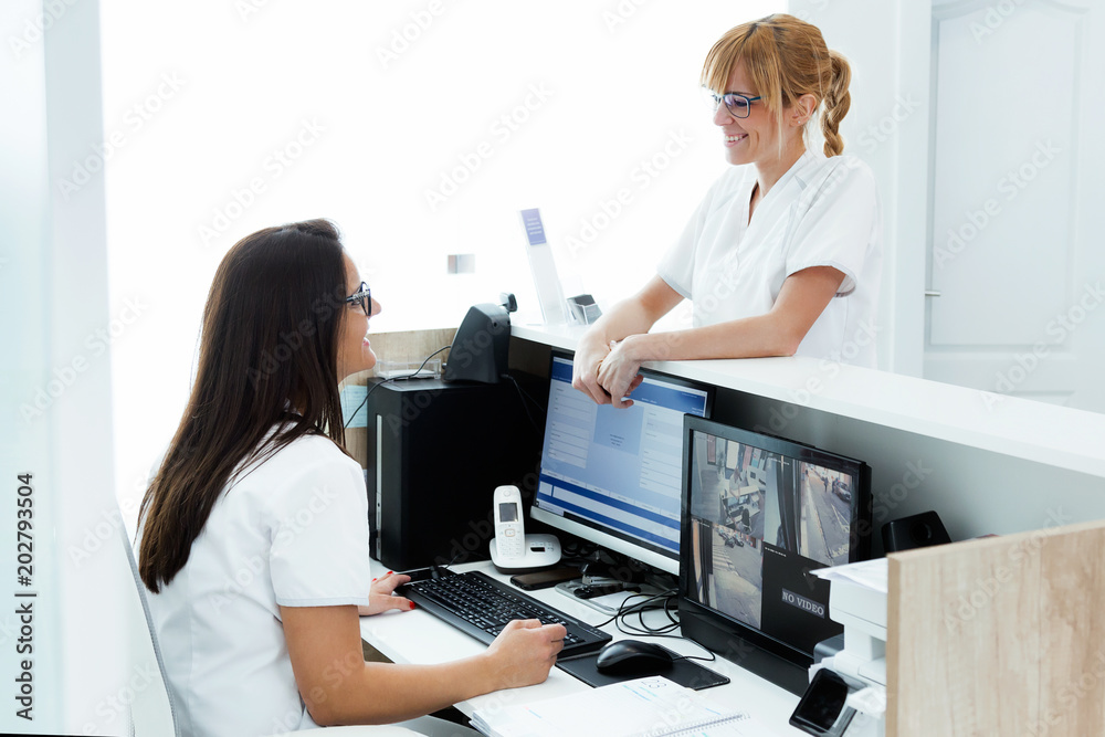 Pretty young beautician talking with receptionist of clinic. - obrazy, fototapety, plakaty 