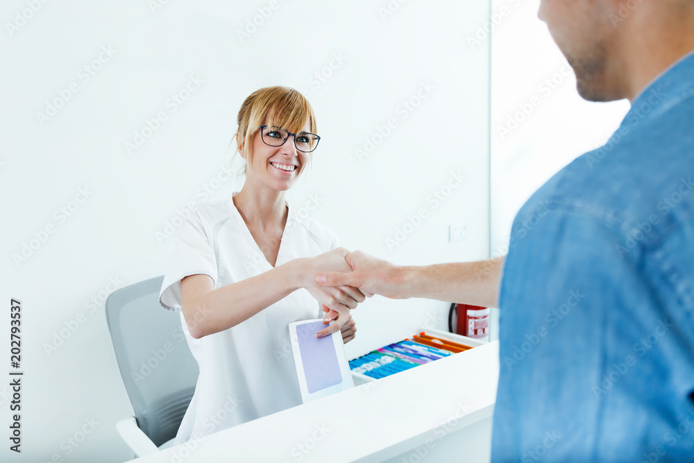 Beautician shaking hands with his male client at the reception of the clinic. Beautician shaking hands with his male client at the reception of the clinic.
